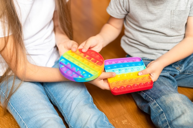 Anti stress sensory pop it toy in a children's hands. a little happy kids sharing and plays with a simple dimple toys at home. 