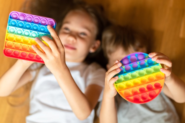 Anti stress sensory pop it toys in a children's hands. a little happy kids plays with a simple dimple toy at home. 