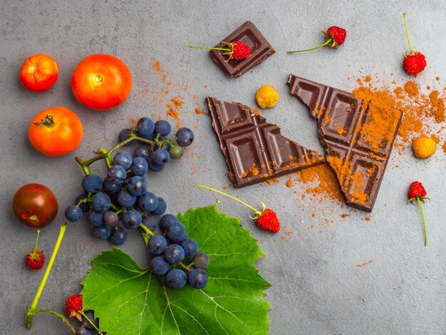 Anticancer food good for cardiovasculas system fresh ripe grape dark chocolate raspberries tomatoes apple on concrete background Food rich in resveratrol antioxidants