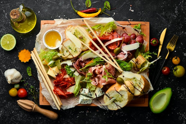 Antipasto Italian food Prosciutto capers salami parmesan honey on a wooden board Top view Rustic style