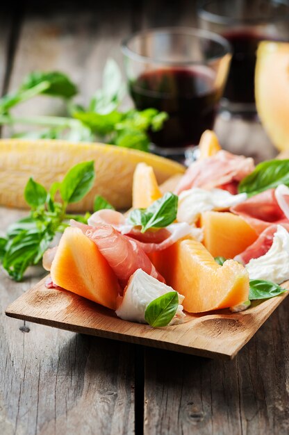 Photo antipasto with melon, mozzarella, ham and basil