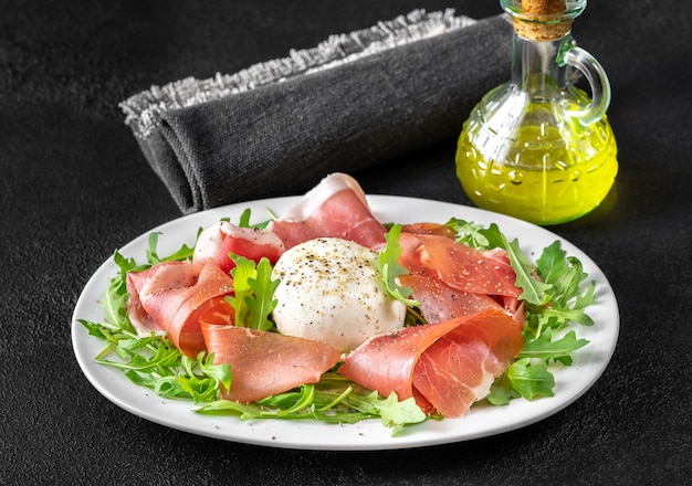 Antipasto with prosciutto , mozzarella and fresh arugula on the serving plate