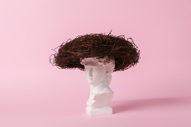 Antique bust of David with nest on a pink background Conceptual pop Minimal still life Creative idea