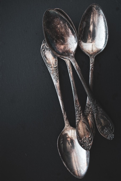 Antique cutlery on black background. Silver spoon isolated, black and white. Silverware with space