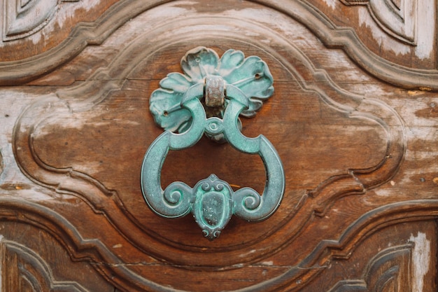 An antique iron door knocker on a wooden door Pisa Italy