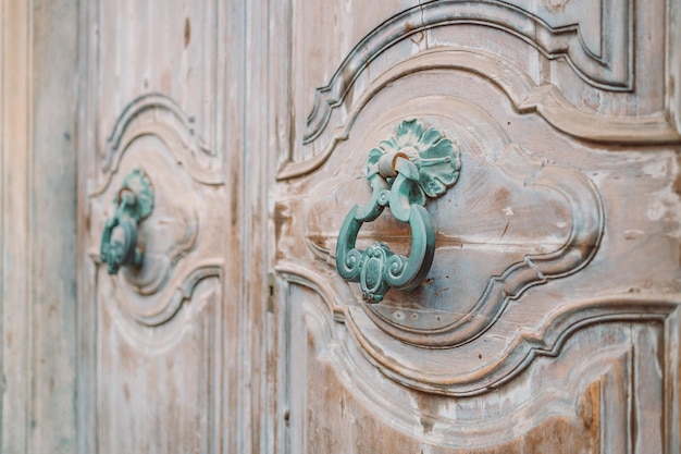 An antique iron door knocker on a wooden door Pisa Italy