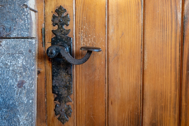 Antique iron handle worn out by the passage of time on a solid wood door