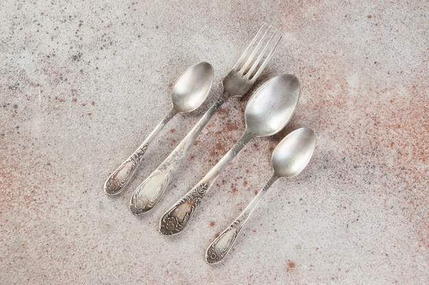 Antique metal cutlery on concrete table.