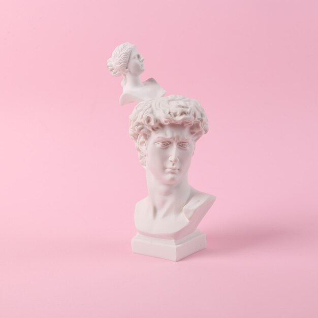 Antique Plaster busts of David and Venus on pink background Conceptual pop Minimal still life photography