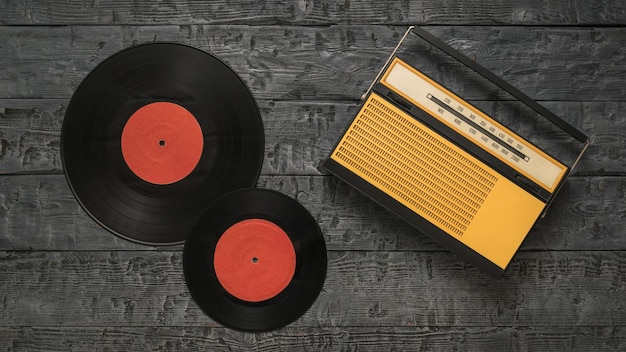 An antique radio and two red vinyl discs on a wooden background Radio engineering of the past time