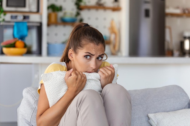 Anxious worried woman sitting on couch at home Frustrated confused female feels unhappy problems in personal life quarrel break up with boyfriend and unexpected pregnancy concept