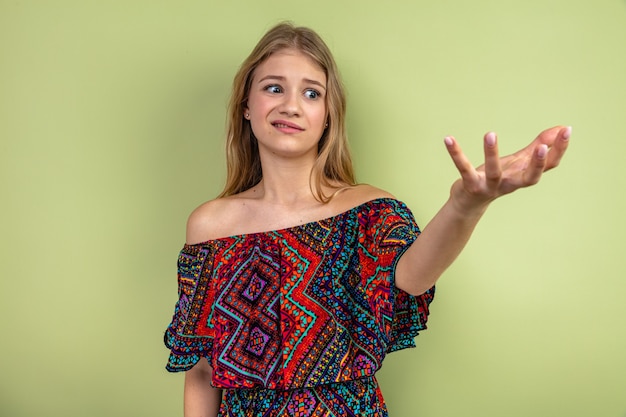 Anxious young blonde woman looking and pointing at side 