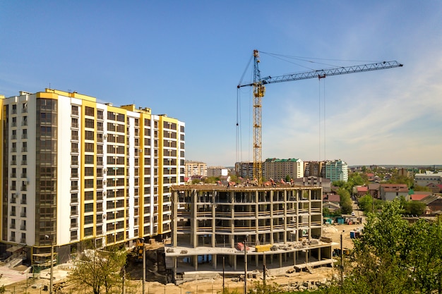 Apartment or office tall building under construction. Working builders and tower cranes