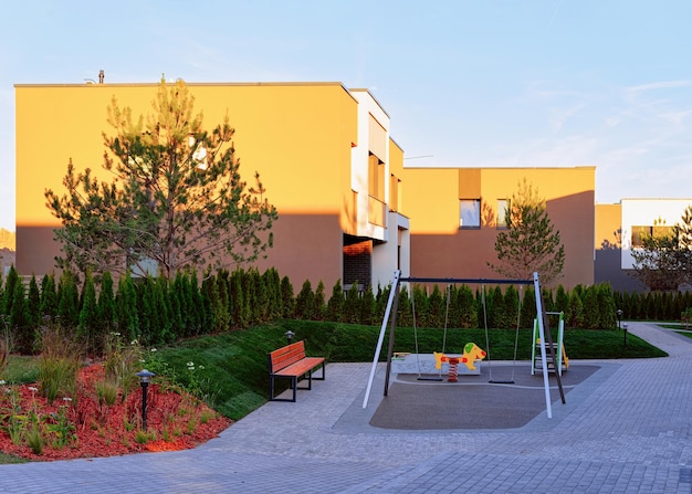 Apartment residential townhouse facade architecture with children playground and outdoor facilities. Blue sky on the background.