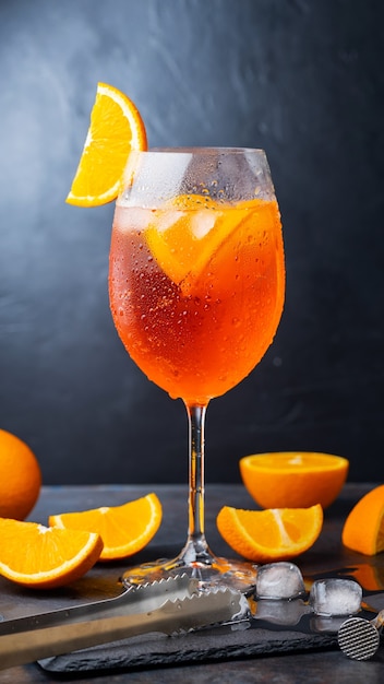 Aperol spritz cocktail and bar accessories. Italian aperol spritz cocktail and a sliced orange on a dark background. Summer cocktail aperol spritz on a slate board