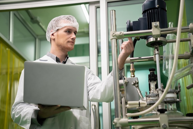 Apothecary scientist recording data from CBD oil extractor in laboratory