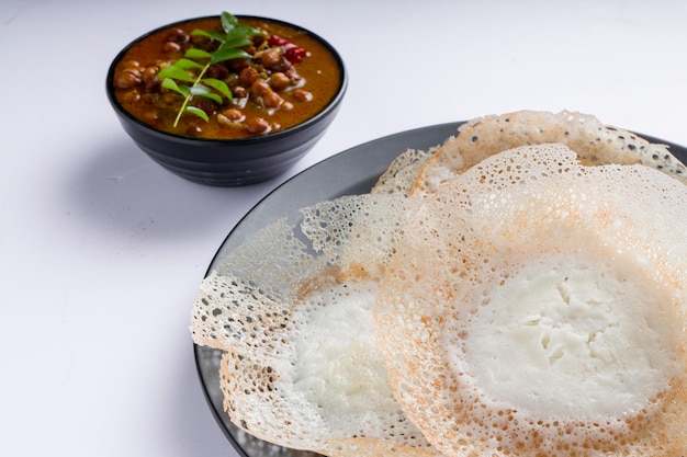 Appam or velliappam or kallappam  or paalappam, tasty delicious  breakfast item in south india and with a good combination of kadala curry or bengal gram curry ,placed on a white background.