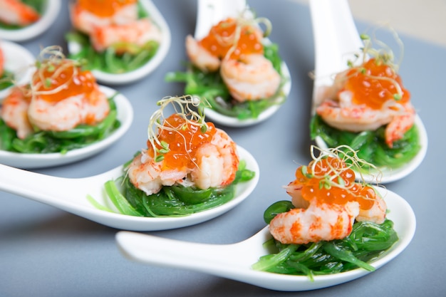 Appetizer from seaweed chuka, crabs and caviar on portioned spoos. Selective focus, close-up.