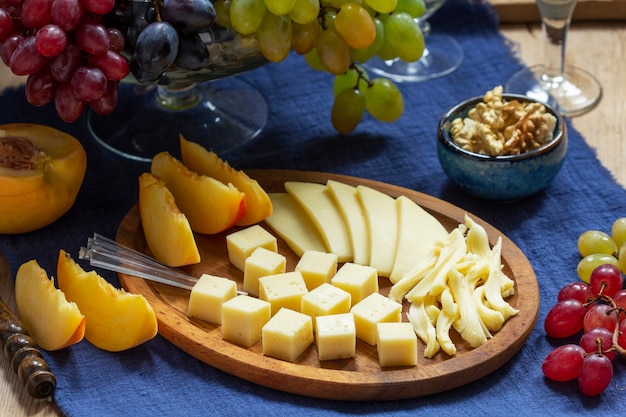 An appetizer of various types of cheese, grapes and walnuts, served with wine. Rustic style.