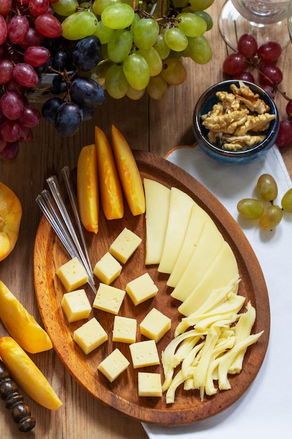 An appetizer of various types of cheese, grapes and walnuts, served with wine. Rustic style.