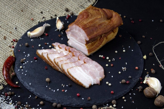 Appetizing baked sliced meat on slate board and black background closeup