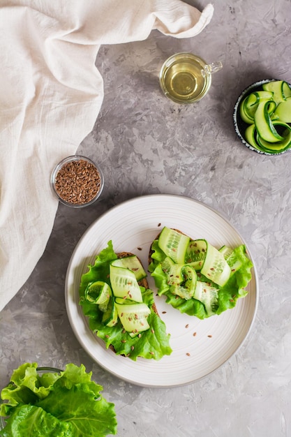 Photo appetizing bruschetta from rye bread lettuce cucumber and flax seeds on a plate on the table healthy diet food top and vertical view