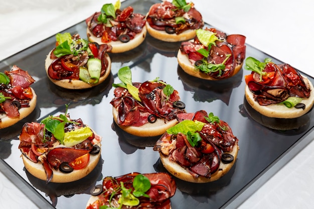 Appetizing canapes with meat sandwiches. Catering for business meetings, events and celebrations.