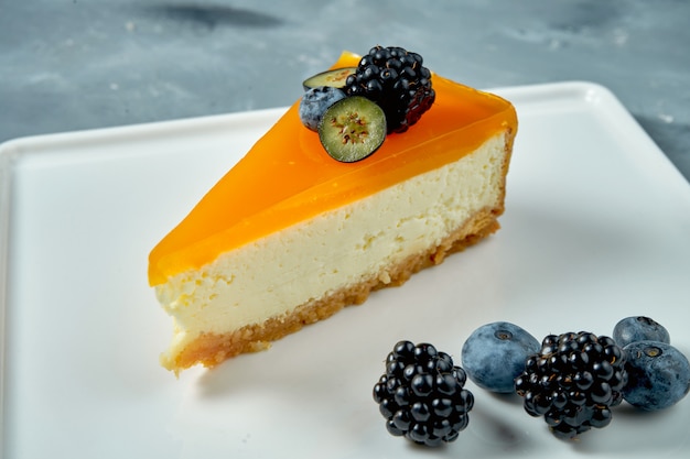 Appetizing dessert - cheesecake with caramel and berries in a white plate. Tasty pastry