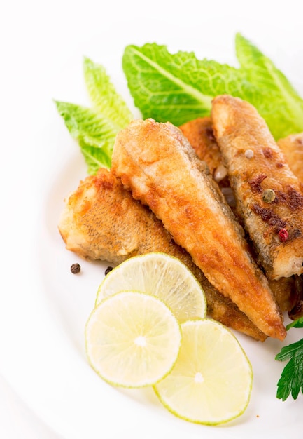 Appetizing fish fillet with vegetables and herbs on a white plate