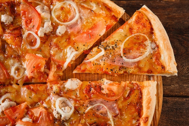 Appetizing fresh baked sliced pizza with tomato, ham, onion and cheese, closeup. Italian traditional fast food, national cuisine.