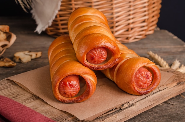 Appetizing fresh culinary pastry - sausages in pastry on wooden background