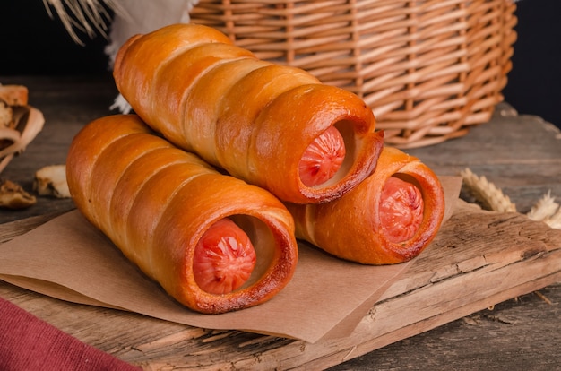 Appetizing fresh culinary pastry - sausages in pastry on wooden background