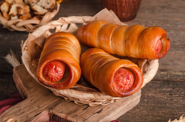 Appetizing fresh culinary pastry - sausages in pastry on wooden background