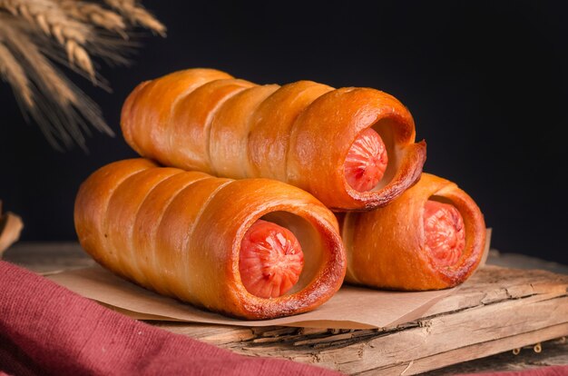 Appetizing fresh culinary sausage pastry on wooden background