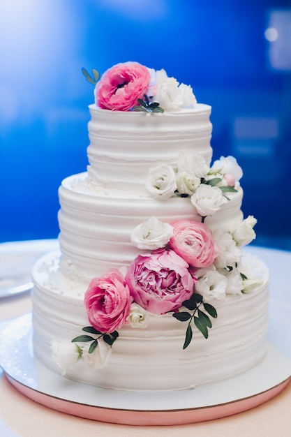 Appetizing fresh pastry cake covered by white cream icing and decorate sweet flower serving on table