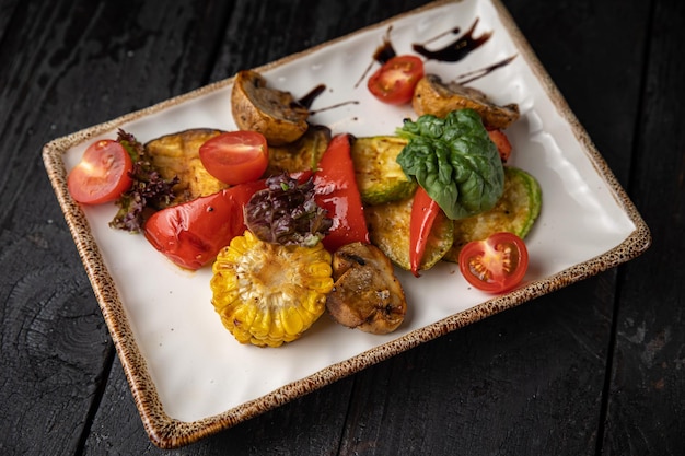 appetizing grilled vegetables on plates on a dark wooden table