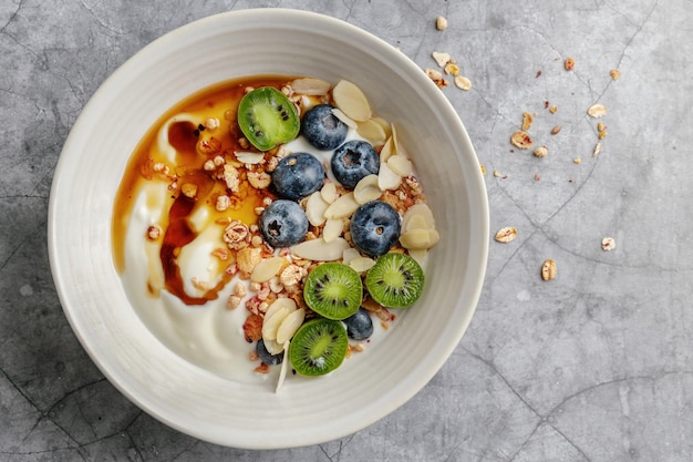 Appetizing homemade muesli with berries and yogurt served in bowl on dark background.