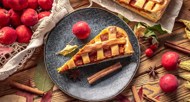 Appetizing homemade pie on a wooden table with garden apples cinnamon and autumn leaves Concept of a cozy atmosphere and autumn mood