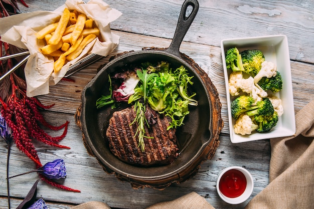 Appetizing juicy beef steak with greens in a pan