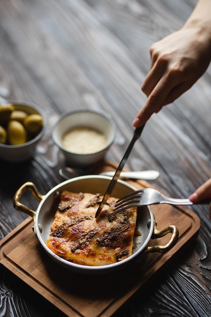 Appetizing lasagna with large olives on a dark background. Food photography