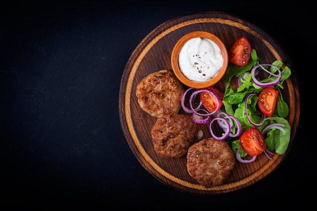 Appetizing meat cutlet and tomato salad with arugula