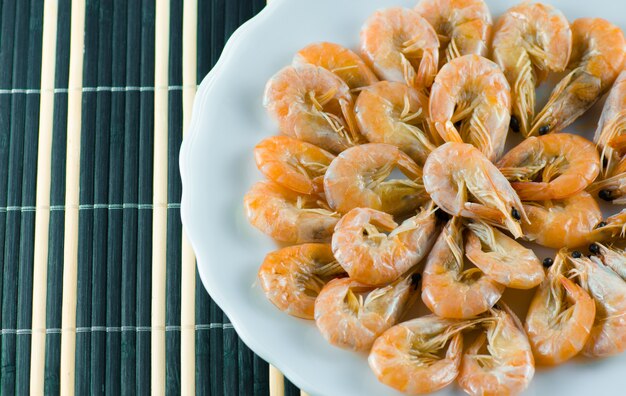 Appetizing shrimps in a white plate lie on a blue napkin in the restaurant