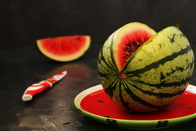 Appetizing striped watermelon with a cut on a dark background Horizontal format Closeup