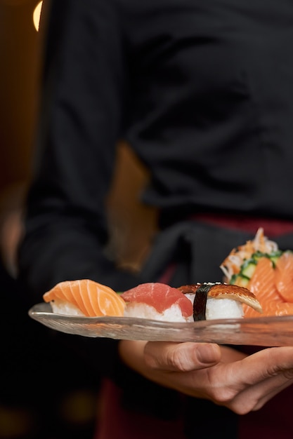 Appetizing sushi on plate in hands of restaurant staff