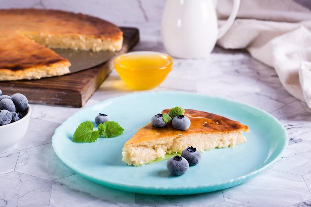 Appetizing thin cheesecake with honey and blueberries on a plate on the table Homemade pastries