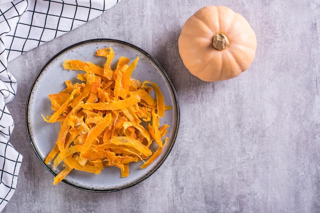 Appetizing vegetarian dessert pumpkin chips on a plate on the table top view