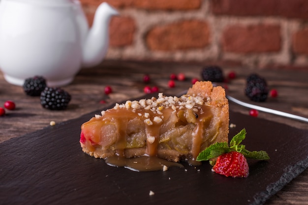 Apple caramel pie on a stone plate on rustic wood table