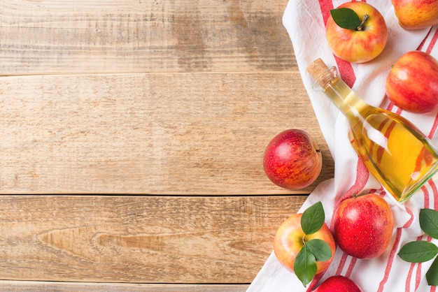 Apple cider vinegar in bottle with apple on wood