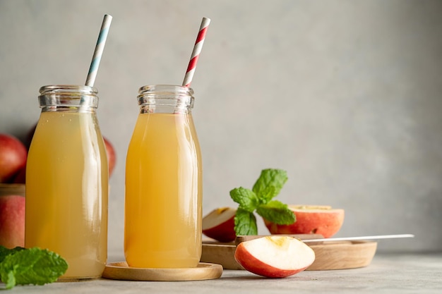 Apple juice glass bottles with fresh red apples wooden background