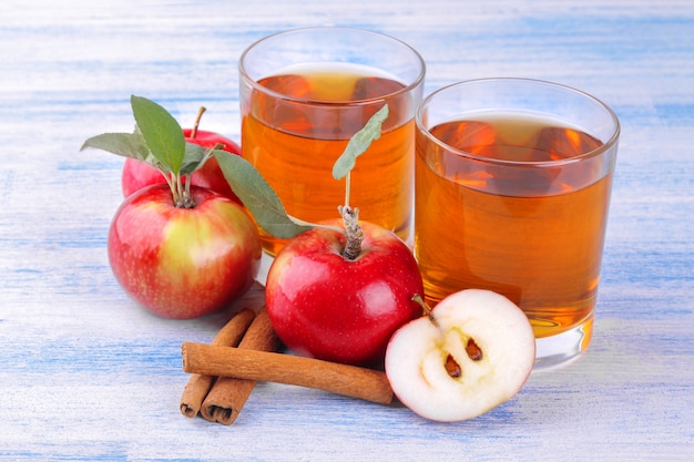 Apple juice with  apples and cinnamon sticks on a wooden background